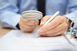 businessman is analyzing through magnifying glass contract and